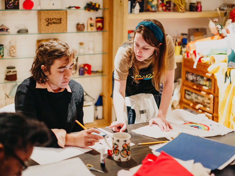 A woman is talking to a man at a vinyl printing class at M.Y.O